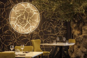 A restaurant interior with a unique wall design, a round illuminated feature, and a table set for two. - Logis Hotel Spa Parenthese (Chille)
