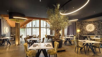 Een modern restaurantinterieur met ronde tafels, stoelen en een centrale boom.