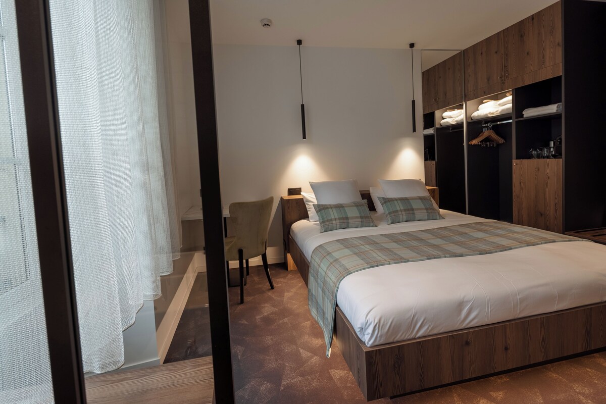 A bedroom with a bed, bedside tables, a chair, and a wardrobe.