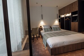 A bedroom with a bed, bedside tables, a chair, and a wardrobe. - Logis Hotel Spa Parenthese (Chille)