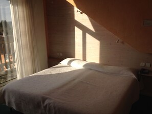 A bedroom with a bed, a window with curtains, and a view of the outside. - Logis Hotel Spa Parenthese (Chille)
