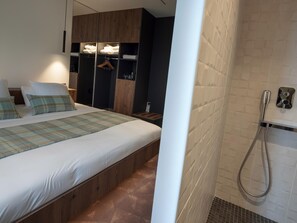 Un dormitorio moderno con una cama grande, un armario de madera y una zona de ducha.