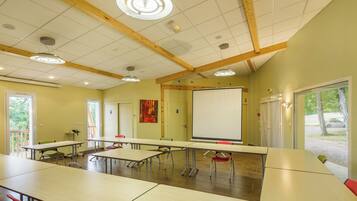 A conference room with tables, chairs, a whiteboard, and a large window.