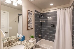 A bathroom with a sink, mirror, and a shower area with a curtain. - Clifftop (St. George)