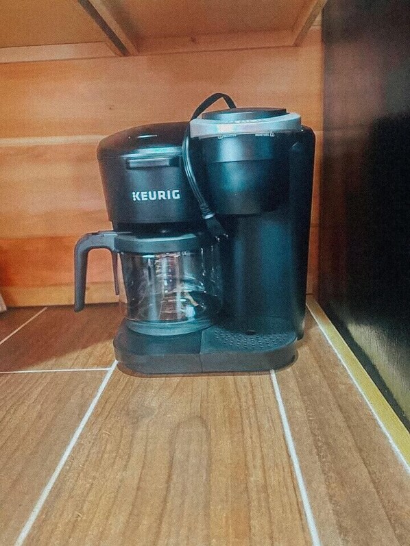 A Keurig coffee maker on a tiled floor.