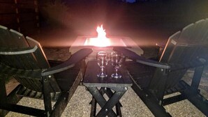 Une table avec deux chaises, placée face à un feu de camp.