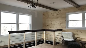 Ein Zimmer mit Holzwänden, einem Metallgeländer und einer Deckenleuchte.