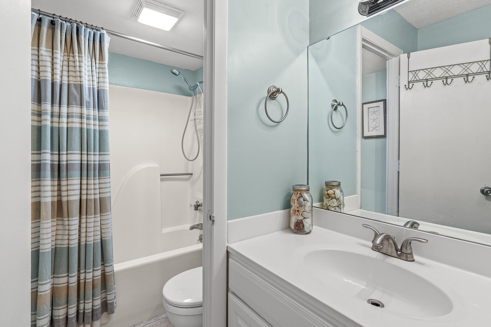 Un bagno con doccia, WC, lavandino e specchio.