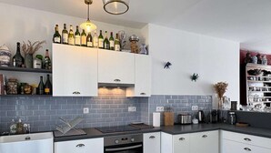 Une cuisine moderne avec des armoires blanches, un four encastré et un plan de travail équipé de divers appareils électroménagers.