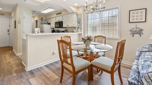A dining area with a round glass table, wooden chairs, and a vase of flowers. - Cozy villas near the heart of North Myrtle Beach (North Myrtle Beach)