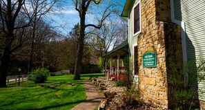 Welcome to The Farm, a charming stone building with a covered porch and beautifully manicured lawn.