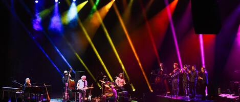 A band performing on a stage with various musical instruments and a keyboard.