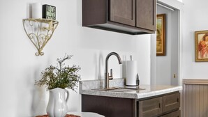 Una cocina moderna con encimera de mármol, grifo de acero inoxidable y armarios oscuros.