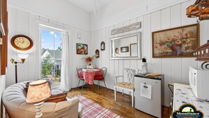 Una habitación acogedora con un reloj antiguo, una mesa de comedor con sillas, un refrigerador y un cuadro en la pared.