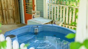 Een hottub in een achtertuin met een houten omheining, een tafel en stoelen.