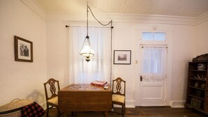 Ein Esszimmer mit Holztisch und -stühlen, einer Kandelaber und einer Tür mit Fenster.
