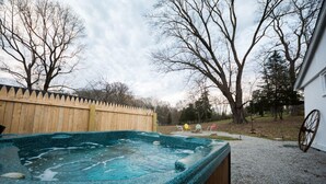Ein Whirlpool in einem Garten mit Holzzaun, Bäumen und einem Kiesweg.