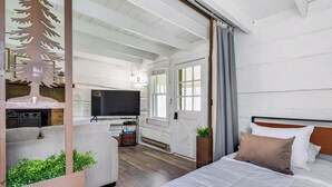 Una camera da letto con un letto, una televisione, un armadio in legno con piante e una finestra.
