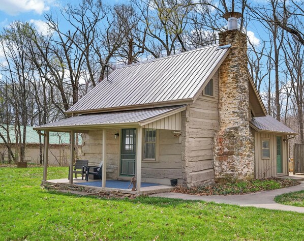 A rustic stone house with a metal roof, a covered porch, and a chimney. - Pet friendly, secluded, close to Nashville! (Nashville)
