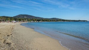 Una playa de piedras, cielo despejado y una montaña al fondo.