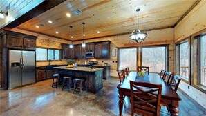 Una cocina amplia con armarios de madera, una isla central y un comedor con una mesa grande y sillas.