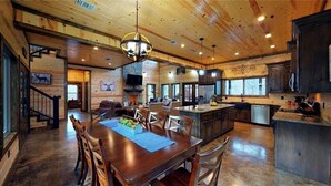 Una cocina amplia con una isla grande, armarios de madera y un respaldo de piedra.