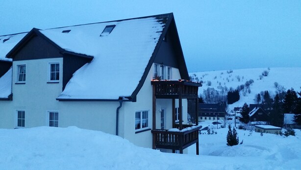 A two-story building with a snow-covered roof and a balcony.