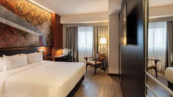 A hotel room with a large bed, a desk, a chair, a TV, and a large mirror.