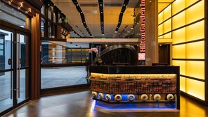 Un hall d’entrée avec un comptoir de réception, une grande porte vitrée et un design moderne au niveau du plafond.