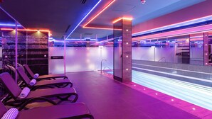 Un hall d’hôtel moderne avec un espace piscine, des chaises longues et un comptoir d’accueil.