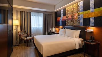 Une chambre d’hôtel avec un grand lit, une chaise, un bureau et une œuvre d’art accrochée au mur.
