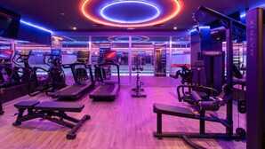 Une salle de sport équipée de tapis de course, de vélos elliptiques et de matériel de musculation.