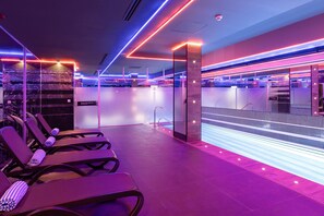 Un hall d’hôtel moderne avec un espace piscine, des chaises longues et un comptoir d’accueil.