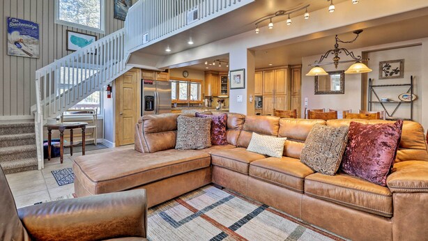 A spacious living area with a large L-shaped sectional sofa, a staircase, and a kitchen in the background. - Hot Tub Relaxation: Breck Gem 3 Mi to Skiing! (Breckenridge)