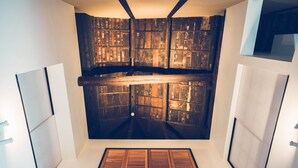 Ein Zimmer mit schrägem Dach, Holzvertäfelung und einer zentralen Lüftungsanlage.