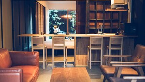 Ein modernes Interieur mit einer Holztheke, Ledersitzmöbeln und Blick auf einen Garten durch eine Glastür.