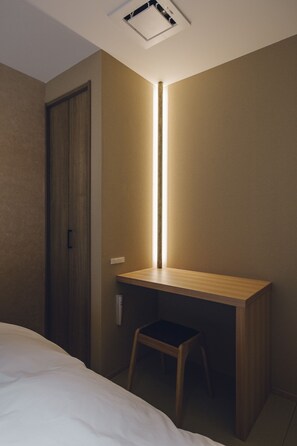 Una camera da letto con una scrivania in legno, una sedia e un letto.