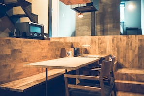 Um restaurante moderno com área de estar em bancos de madeira, uma mesa comprida e uma televisão na parede.