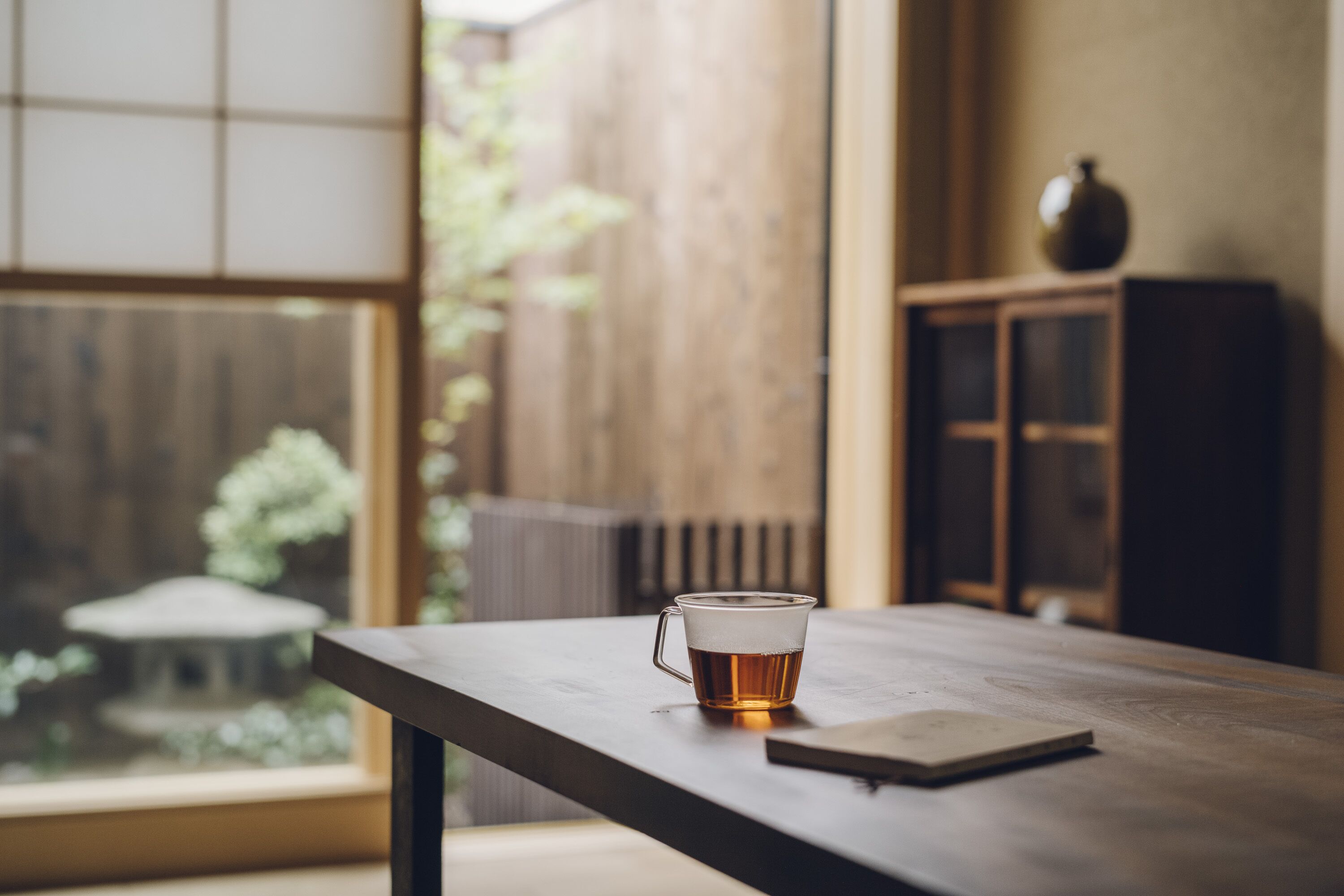Une table en bois avec une tasse de thé en verre et un carnet.