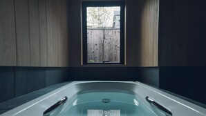 A modern bathroom with a freestanding bathtub, wooden panel walls, and a window overlooking a tree. - Someno House Kyoto Dog Friendly (Kyoto)