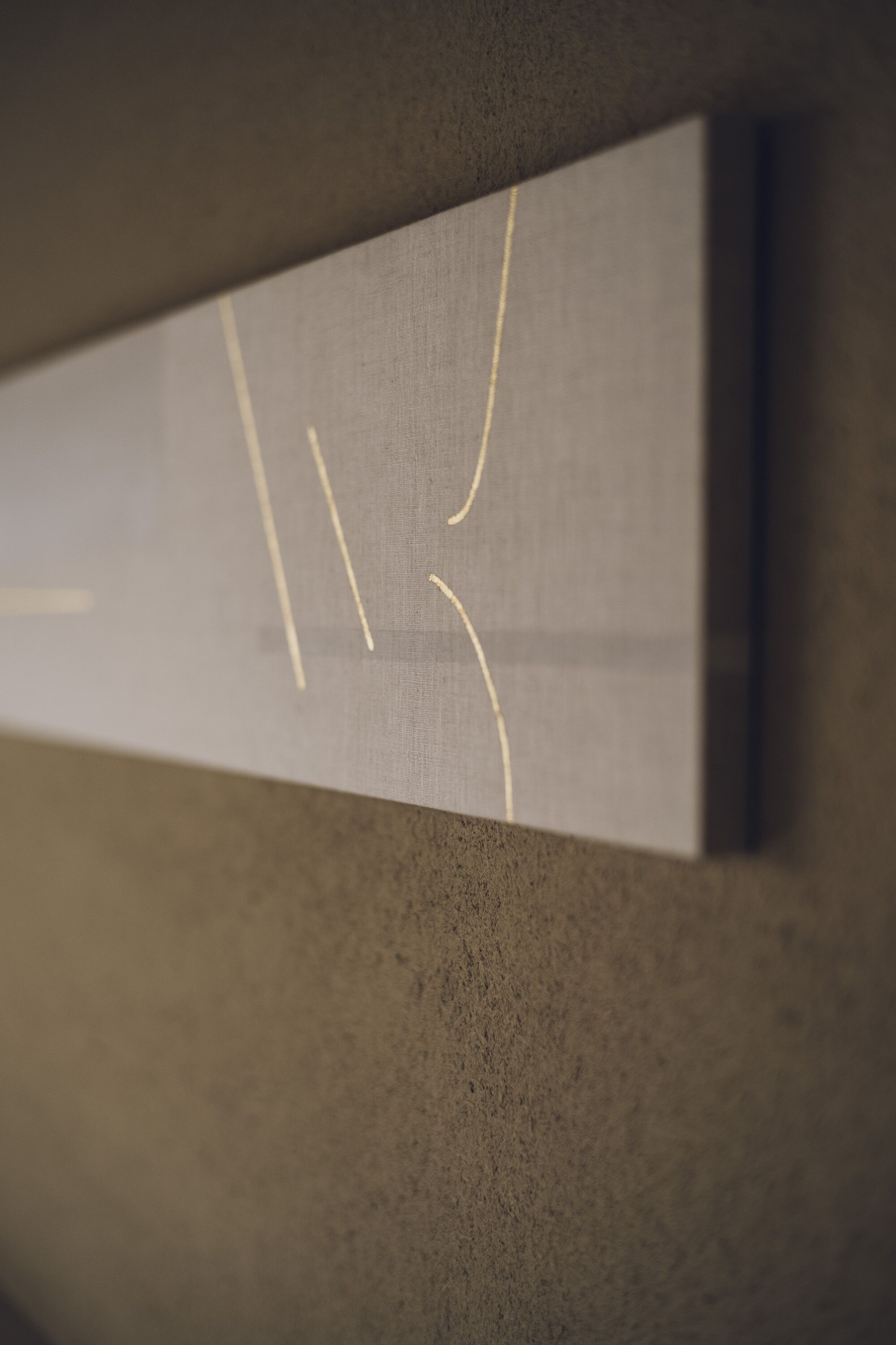 Ein Detailaufnahme einer Wand mit strukturierter Oberfläche, geometrischem Muster und einer eingelassenen Fläche.