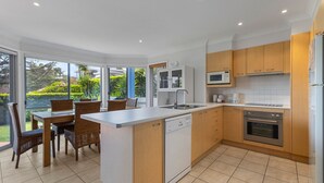 Eine moderne Küche mit Geschirrspüler, Backofen, Mikrowelle und einem Essbereich mit Korbstühlen und einem Tisch.