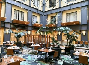 Enjoy meals in a stylish dining area with tables, chairs, and potted plants.