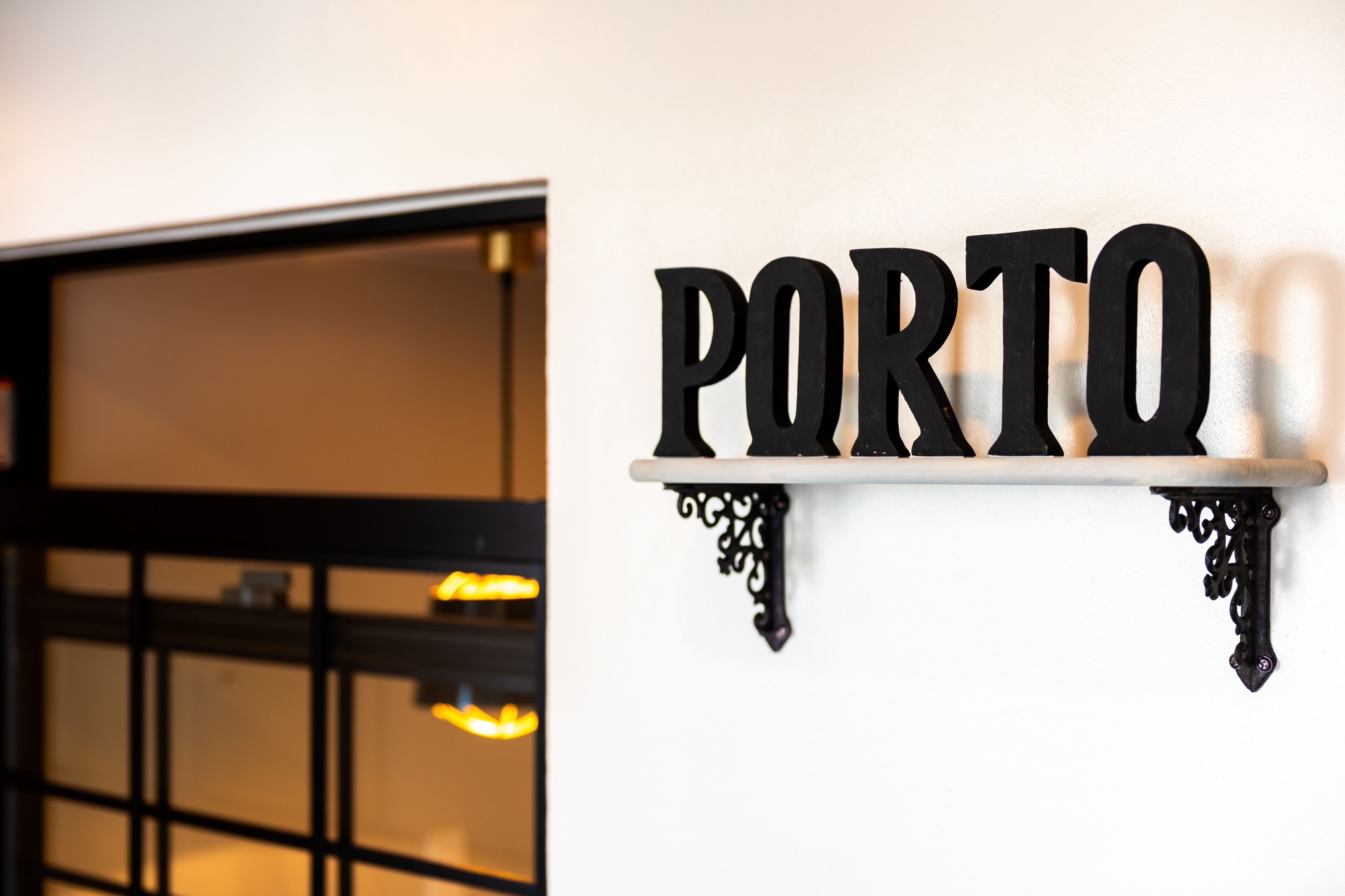 A sign with the word "PORTO" mounted on a white wall.