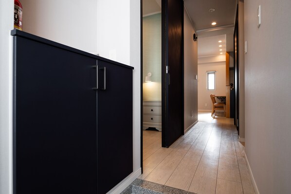 Un couloir avec une armoire sombre, un plancher en bois et une chaise au loin.