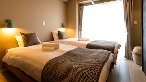 Een hotelkamer met twee bedden, elk met een bedsprei met dessin, een nachtkastje en een lamp.