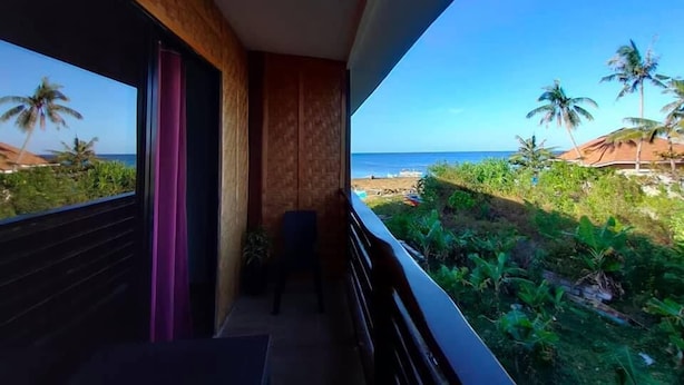 A balcony with a view of the ocean and palm trees. - Mystic Divers Guesthouse (San Juan)