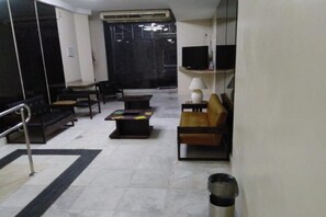 A hotel room with a sofa, a coffee table, a TV, and a lamp. - Center Hotel (Rio de Janeiro)