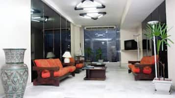 A modern living room with a sofa set, a coffee table, a decorative vase, and a television.