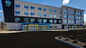 A modern hotel building with a blue and gray facade, multiple windows, and a clear sky. - Tru by Hilton Alcoa Knoxville Airport (Alcoa)